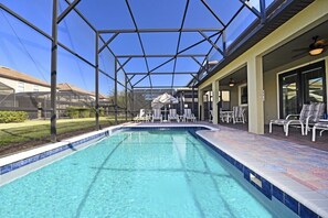 Ein überdachter Pool im Freien mit klarem, blauem Wasser, umgeben von Liegestühlen und einer Terrassenfläche.