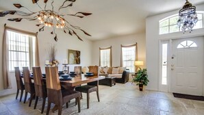 A spacious dining area with a wooden table and chairs, a chandelier, and a large window providing natural light. - 1802nhd (Davenport)