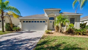 A single-story house with a garage, surrounded by a well-maintained lawn and palm trees. - 1802nhd (Davenport)