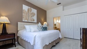 A bedroom with a bed, bedside lamps, a nightstand, a wall art piece, a wardrobe, and a ceiling fan. - 1802nhd (Davenport)