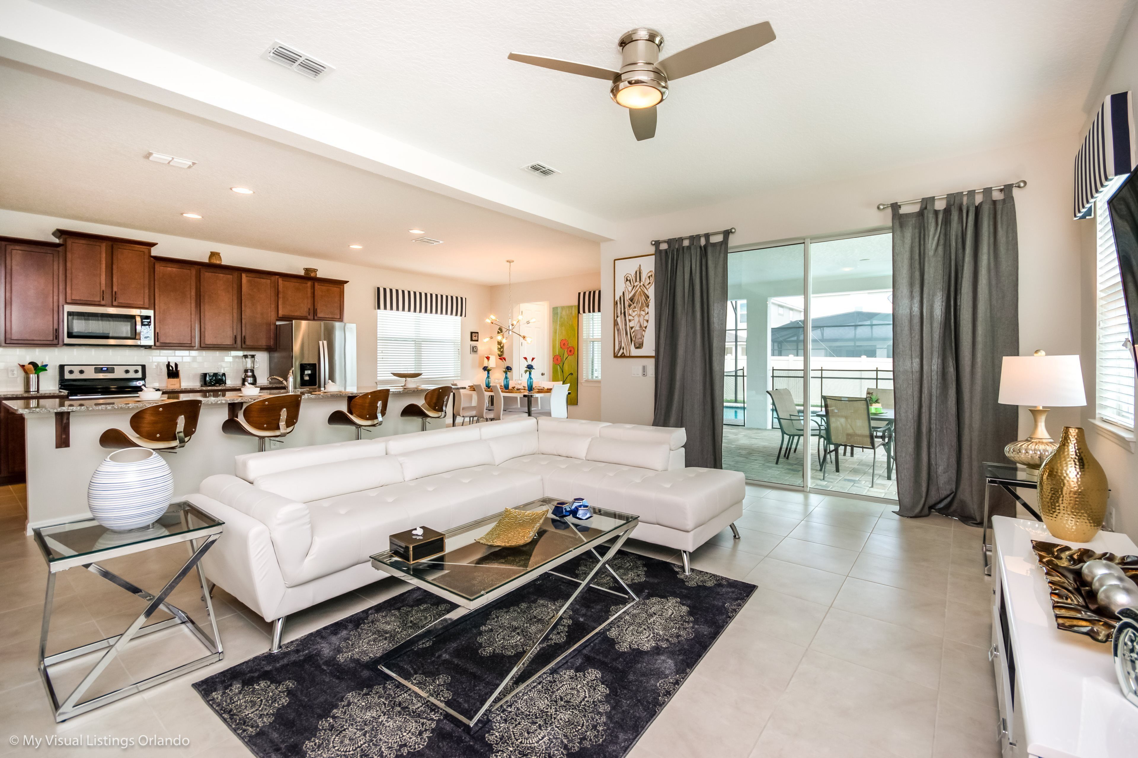 A modern living room with a white sectional sofa, a glass coffee table, and a black rug.