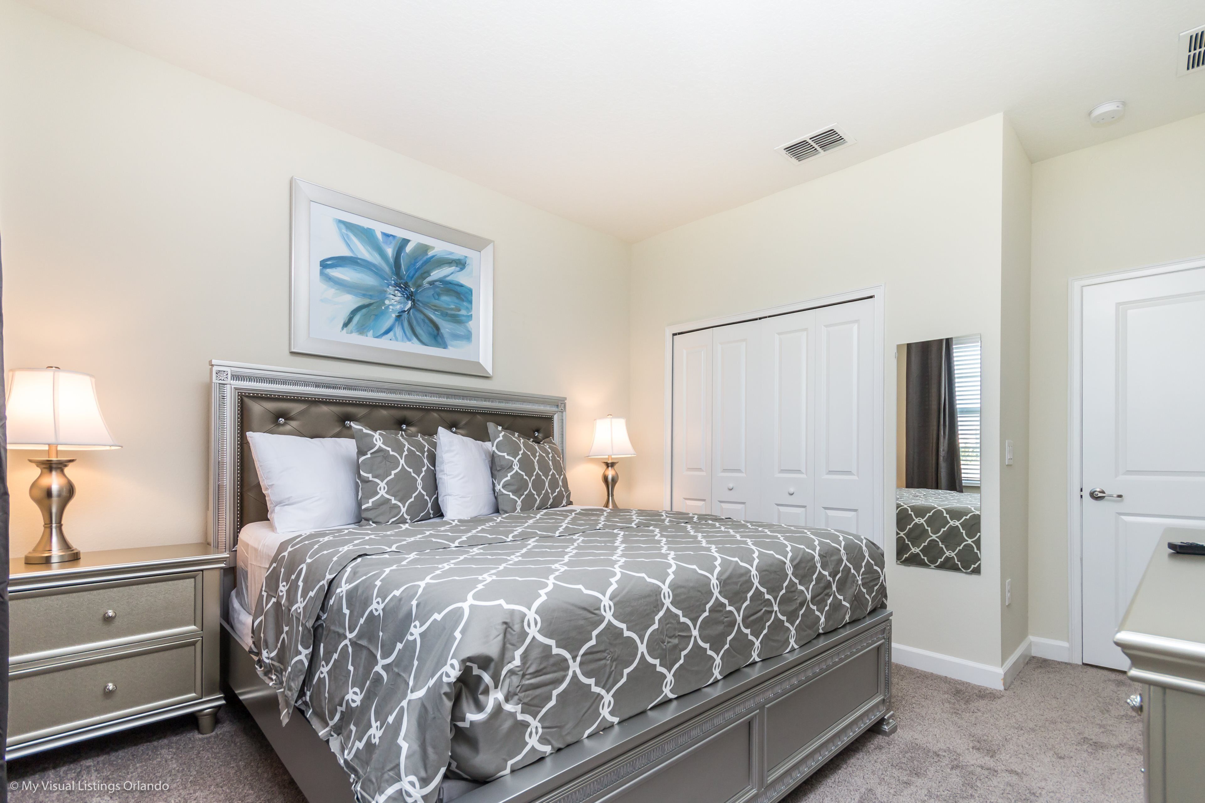 A bedroom with a bed, nightstands, a dresser, a door, and a window with curtains.
