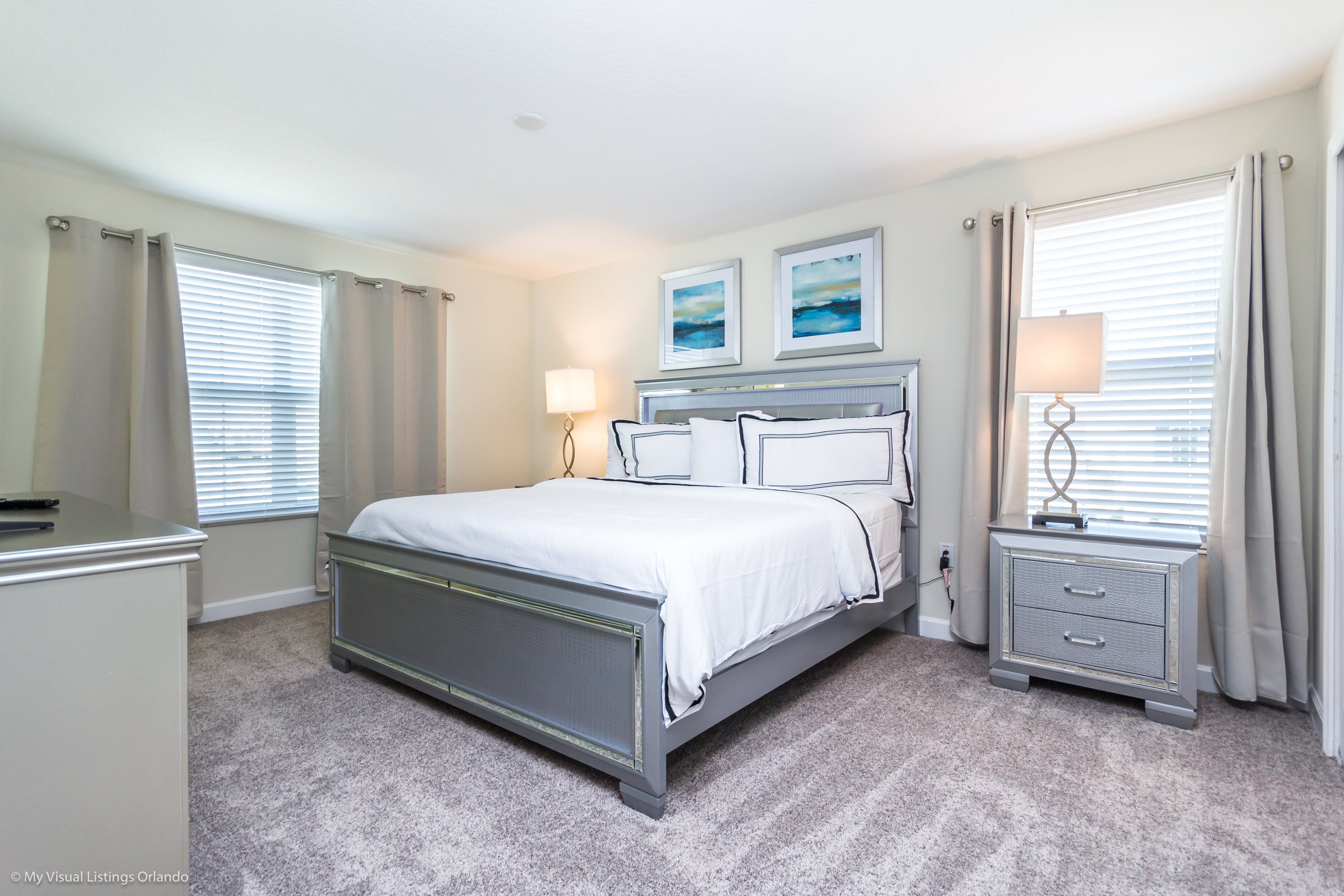 A bedroom with a bed, bedside tables, a dresser, and a window with curtains.
