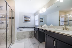 A modern bathroom with a glass shower enclosure, a large mirror, and a double sink vanity. - Champions Gate 6 Bedroom 5 BH (Davenport)