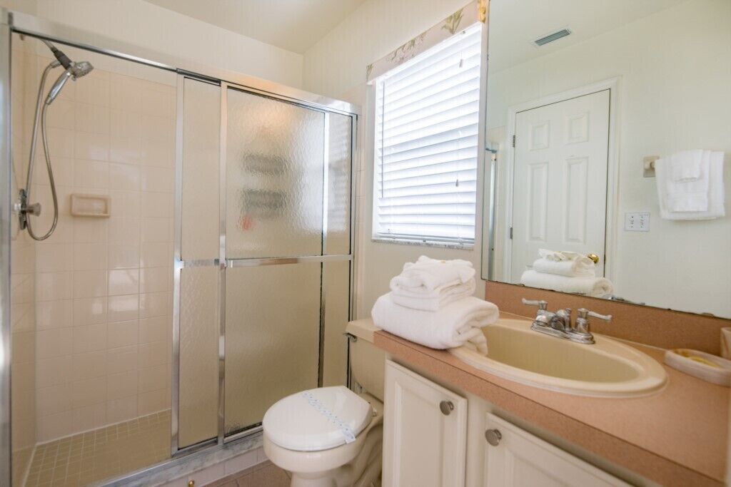Une salle de bain avec une douche à parois de verre, des toilettes, un lavabo et un miroir.