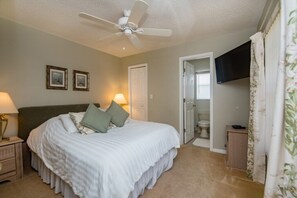 A bedroom with a bed, bedside lamps, a ceiling fan, a television, and a door leading to a bathroom. - 4 Bedroom 3 Bathroom Pool Villa (Davenport)