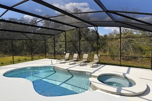 A swimming pool with a hot tub, surrounded by a covered area with chairs.