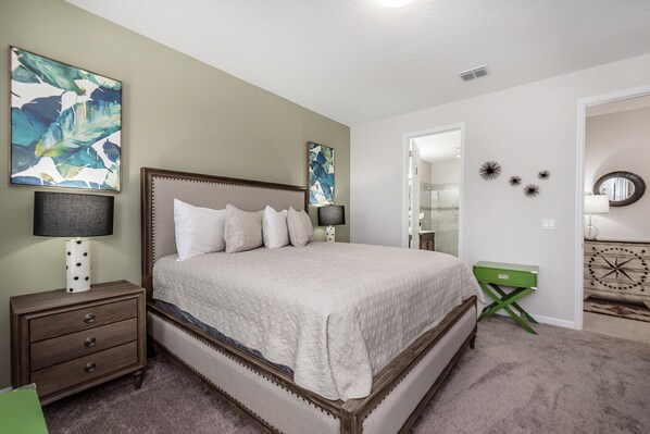 A neatly arranged bedroom with a large bed, two bedside tables, and a green side table.