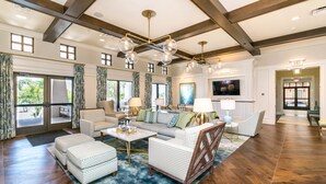 A spacious living room with a high ceiling, wooden beams, a large sofa set, a coffee table, and a television. - Amazing 6 Bedroom 5 Bathroom Solara Resort Villa (Kissimmee)