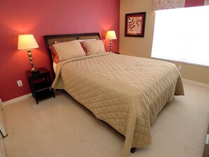 Un dormitorio con una cama, dos lámparas de noche, una mesita de noche, una ventana con persianas y una obra de arte floral en la pared.