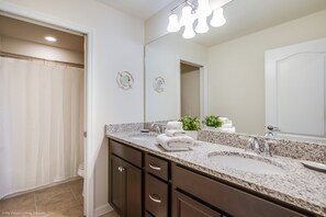 A bathroom with a granite countertop, a sink, a mirror, and a shower curtain. - 1631la Luxury 6 Bed Villa With Pool & Spa (Kissimmee)