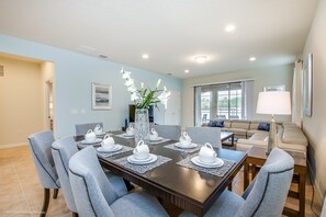 A dining area with a rectangular table set for six, surrounded by six grey upholstered chairs.