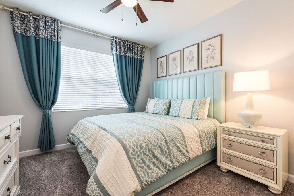 Une chambre à coucher comprenant un lit, une table de chevet, une commode et un ventilateur de plafond.