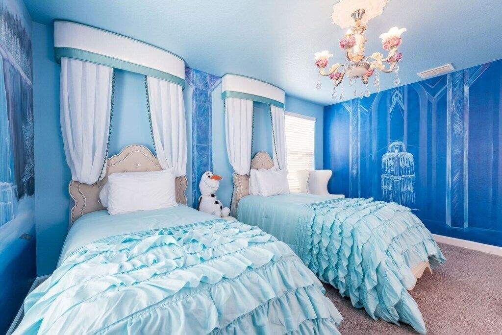 A bedroom with two beds, a chandelier, and a mural on the wall.