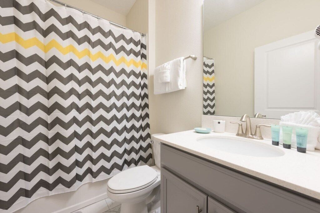 Een badkamer met een witte wastafel, een spiegel en toiletartikelen op het aanrecht.