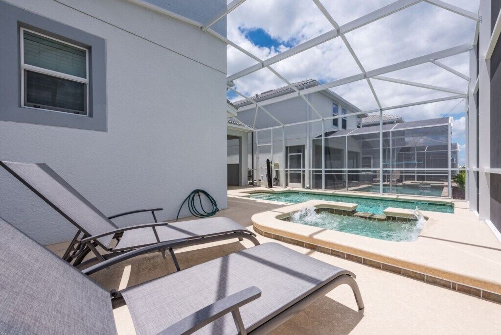 Un espace piscine intérieure comprenant des chaises longues, un jacuzzi et un espace clos par des parois de verre.