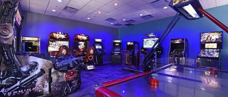 A gaming arcade with multiple arcade machines and a large screen.