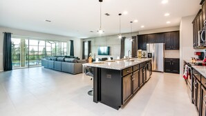 Una cocina moderna con una isla grande, muebles oscuros y electrodomésticos de acero inoxidable.
