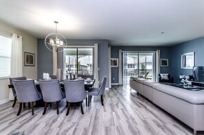 A modern living room with a dining area, grey walls, and a large window. - 6 Bedroom Golf Course Resort Villa (Davenport)