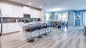 Een moderne keuken met witte kasten, een granieten aanrechtblad en een centraal eiland met barstoelen.