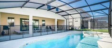 Piscina interior con cerramiento de vidrio, sillas de descanso y zona de terraza.