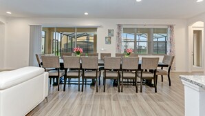 Un espace repas comprenant une grande table et des chaises, un banc et une vue à travers une porte vitrée.