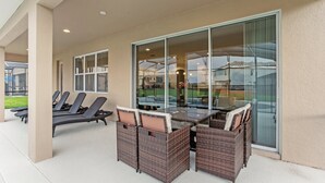 Une terrasse extérieure aménagée avec des meubles en osier, une porte vitrée et une vue sur les environs.