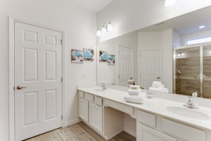 A modern bathroom with a large mirror, white cabinetry, and a double sink.