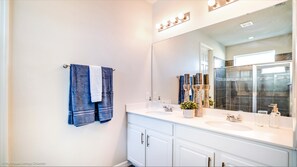 A bathroom with a white vanity, a large mirror, and a towel rack with two towels. - 1749carri (Kissimmee)
