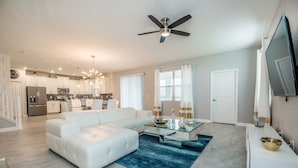 A modern living room with a white sofa, a glass coffee table, and a blue rug. - 6 Bed 5 Ba Villa with Games, Pool & Spa (Davenport)