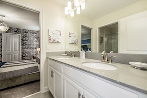 A bathroom with a double sink, a large mirror, and a shower area.