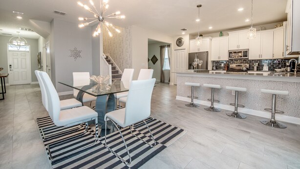 A modern kitchen with white cabinets, a stainless steel refrigerator, and a bar area with stools. - 6 Bed 5 Ba Villa with Games, Pool & Spa (Davenport)