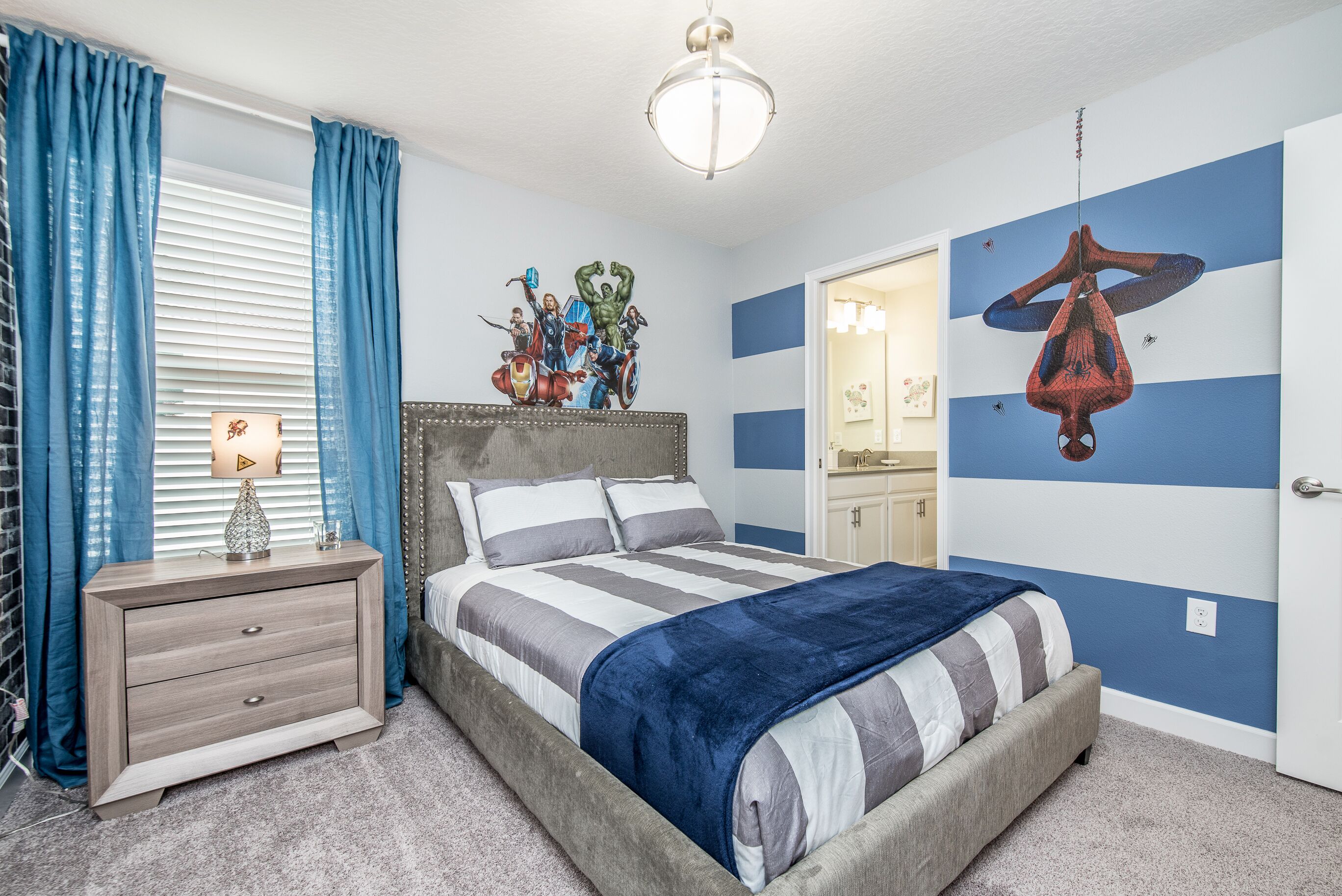 A bedroom with a bed, a nightstand, a dresser, a wall mural, and a hanging spider web decoration.