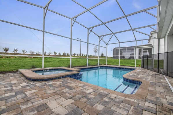 A swimming pool with a brick deck and a glass enclosure.