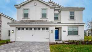 A two-story house with a white exterior, a garage, and a blue door. - 6 Bed 5 Ba Villa with Games, Pool & Spa (Davenport)
