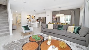 A modern living room with a grey sofa, a coffee table, and a staircase. - 4832ds (Kissimmee)