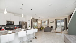 A modern kitchen with white cabinets, a central island with bar stools, and stainless steel appliances. - 4832ds (Kissimmee)