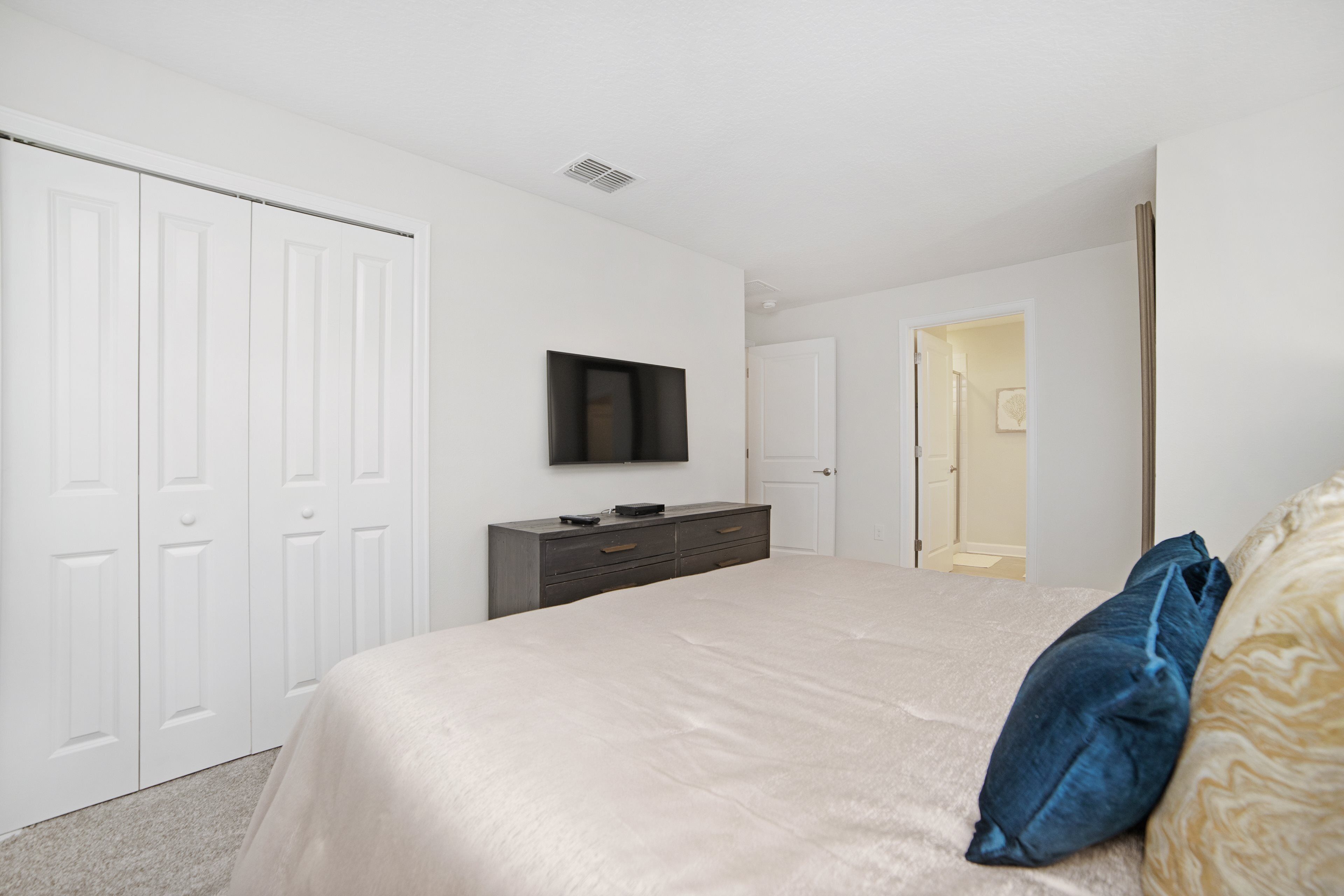 Een slaapkamer met een bed, een dressoir, een televisie en een kledingkast.