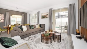 A modern living room with a sofa, coffee table, and dining area. - 4832ds (Kissimmee)