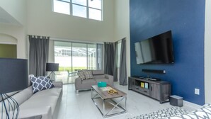 A modern living room with a sofa, coffee table, TV, and entertainment unit.
