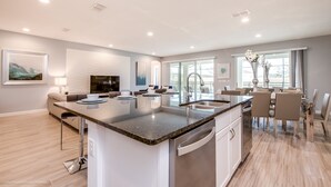 Uma cozinha moderna com uma ilha central, eletrodomésticos de aço inoxidável e uma área de refeições com mesa e cadeiras.
