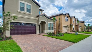 A residential building with a brick driveway, a garage, and a well-maintained lawn. - 8 BD 6 BH House Villa at West Side (Kissimmee)