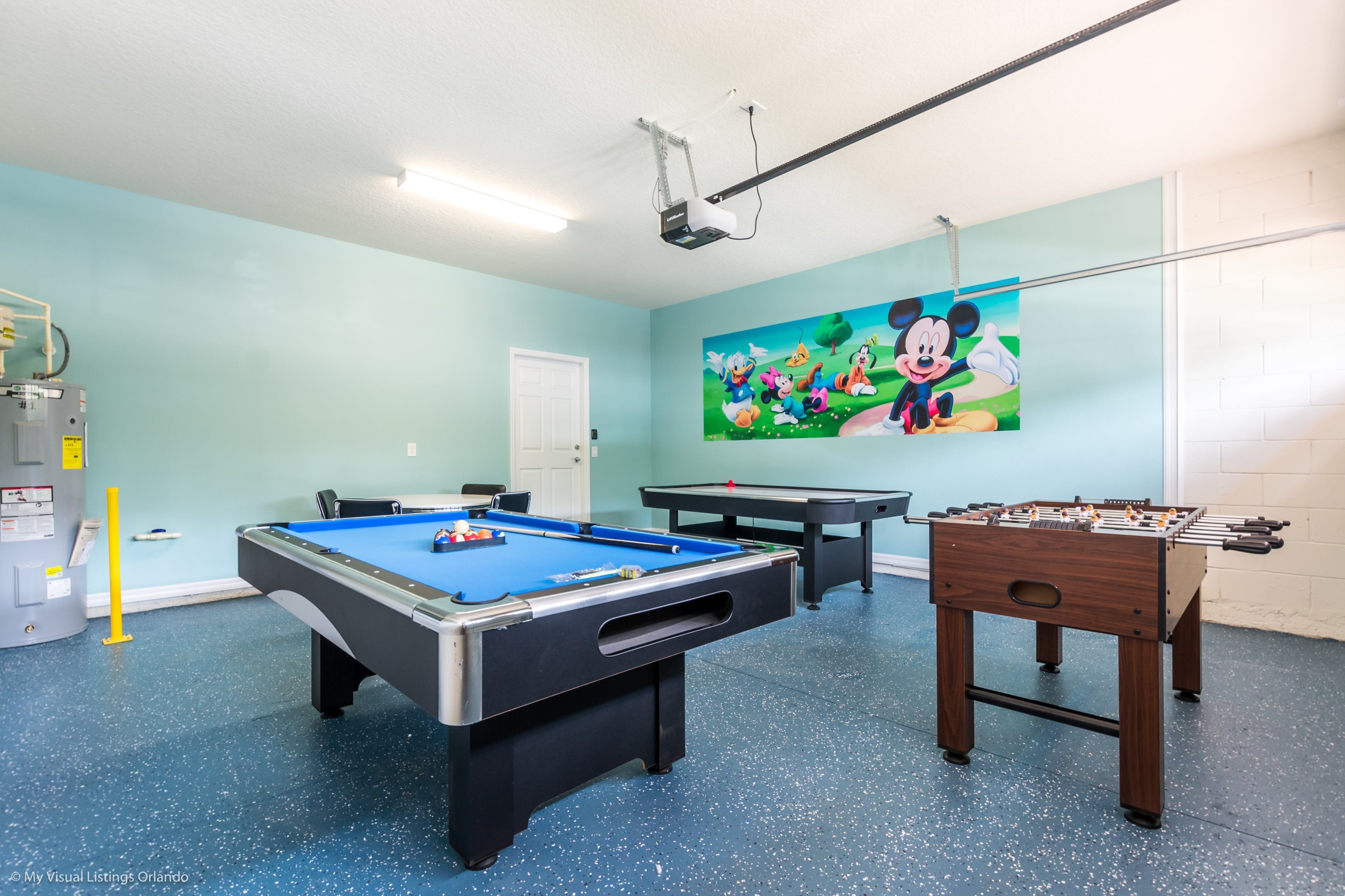 A room with a pool table, foosball table, and a projector screen.