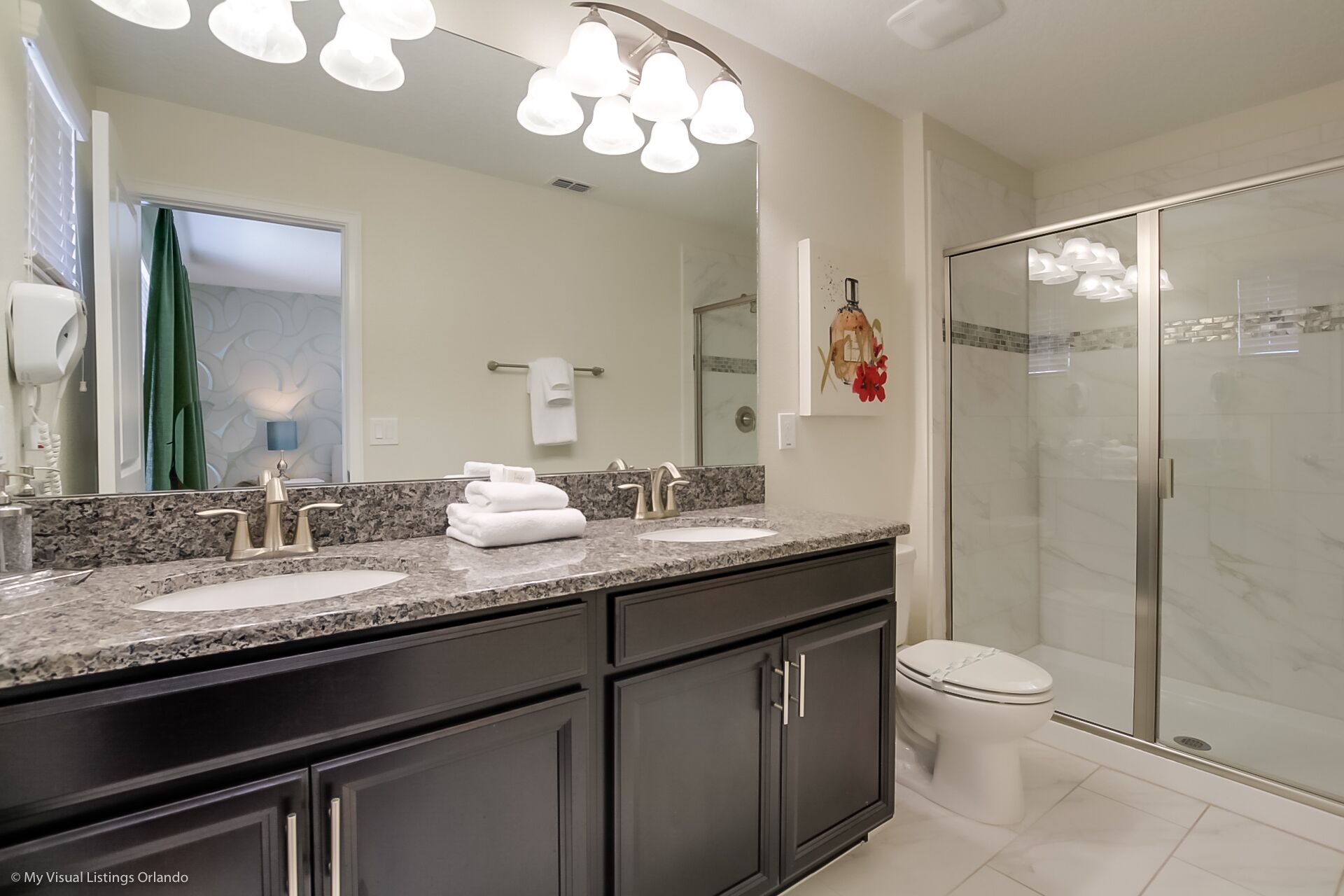 A bathroom with a double sink vanity, a toilet, and a walk-in shower.