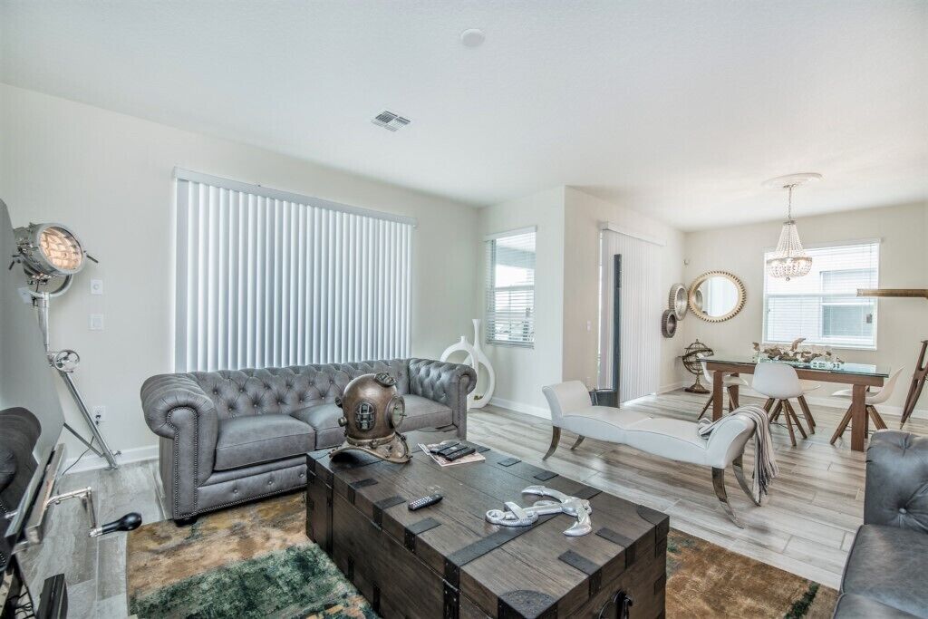 A spacious living room with a grey sofa, a coffee table, and a dining area with a table and chairs.