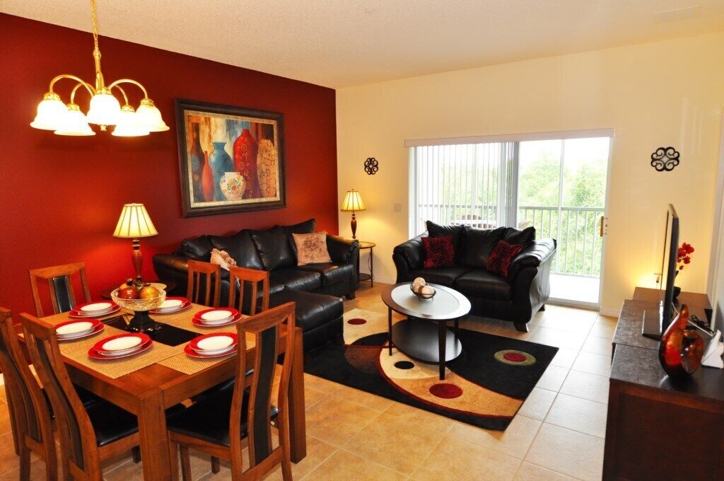 A living room with a dining area, two sofas, a coffee table, and a painting on the wall.