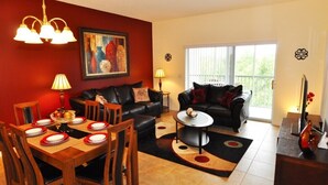 A living room with a dining area, two sofas, a coffee table, and a painting on the wall. - Sun Lake IHR 3062 (Kissimmee)