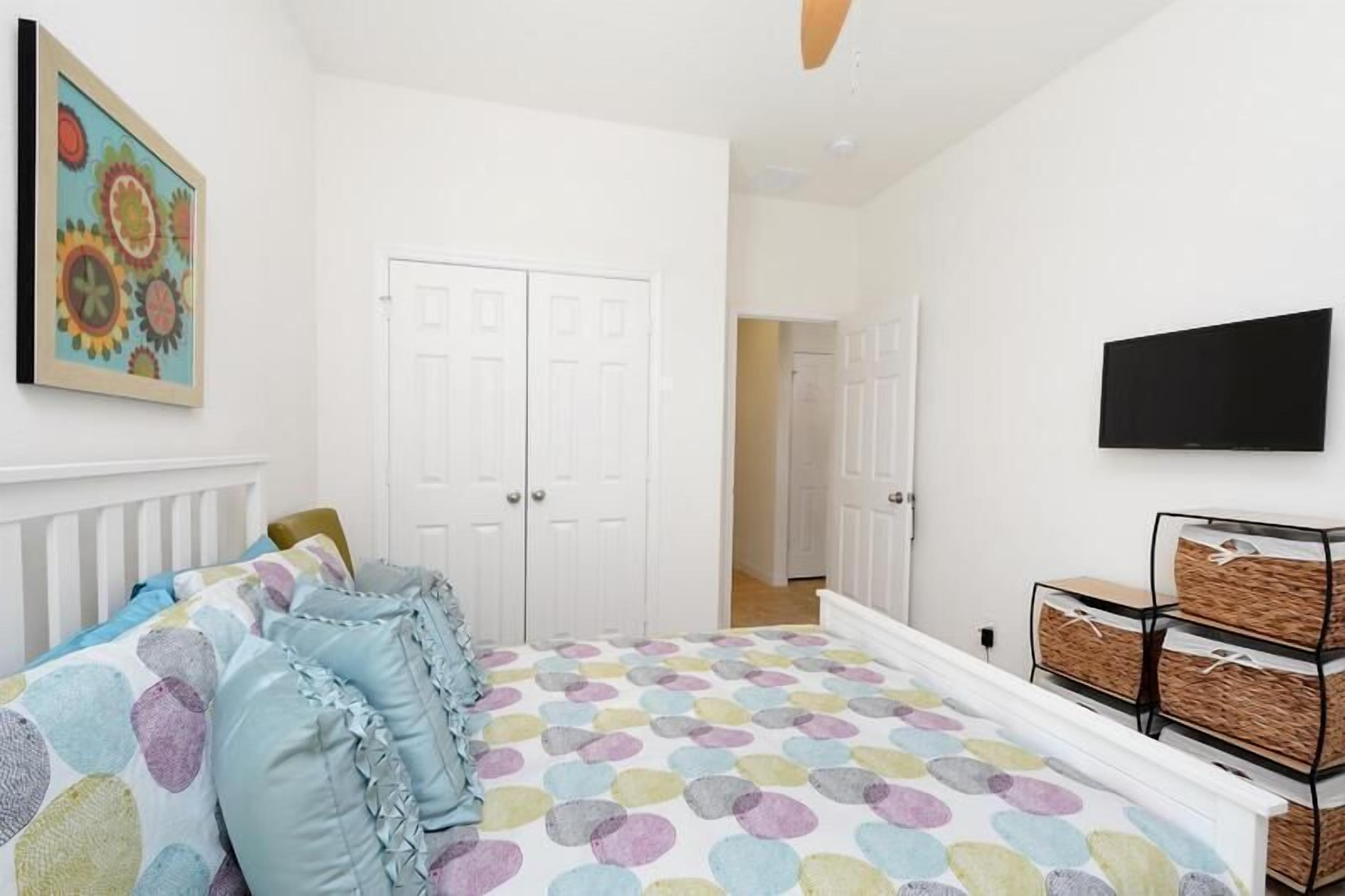 Un dormitorio con cama, armario blanco y televisor.
