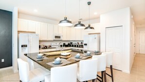 A modern kitchen with white cabinets, a granite countertop, and a central island with seating.