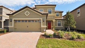 A two-story residential building with a beige facade, a red door, and a garage. - Champions Gate - 1457gmsil (Kissimmee)